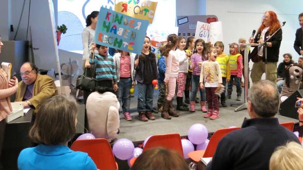 Eine Gruppe Kinder demonstriert mit Schildern für ihre Rechte auf einer Bühne.