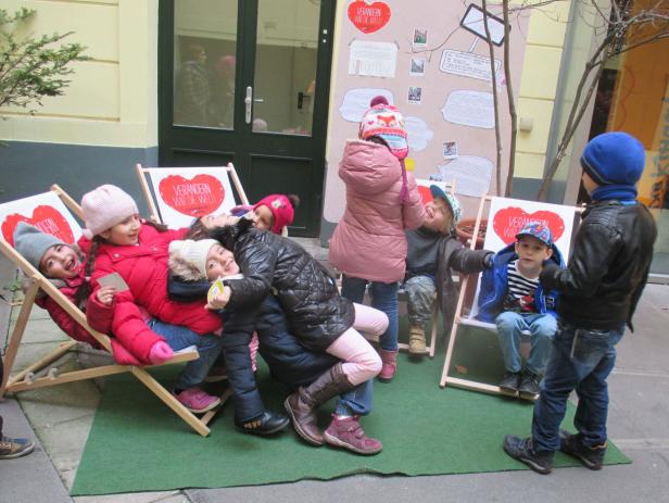 Eine Gruppe Kinder sitzt und steht um Liegestühle mit der Aufschrift „Verändern wir die Welt!“.