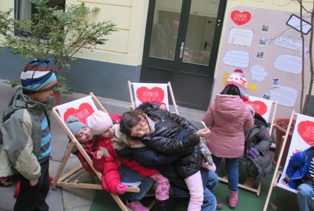 Eine Gruppe Kinder sitzt und steht vor Liegestühlen mit der Aufschrift „Verändern wir die Welt“.