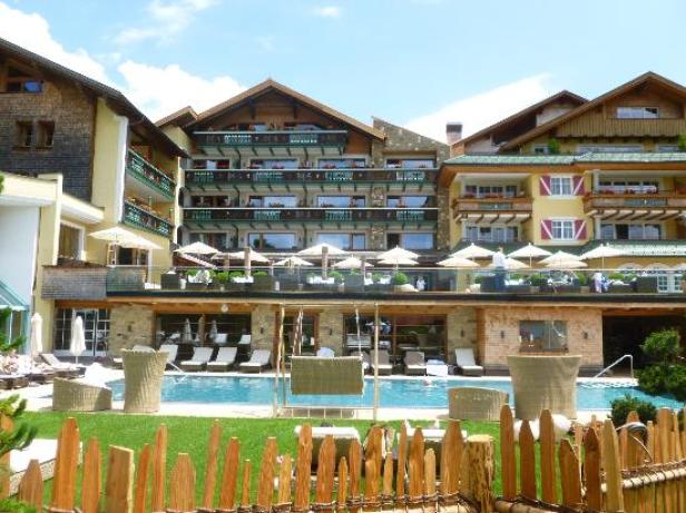 Ein Hotel mit Pool und Liegestühlen hinter einem Holzzaun.