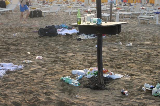 Ein verschmutzter Strand mit Müll und zurückgelassenen Gegenständen.