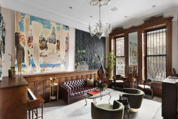 Ein Wohnzimmer mit einem Klavier, einem Sofa und einem großen abstrakten Gemälde.