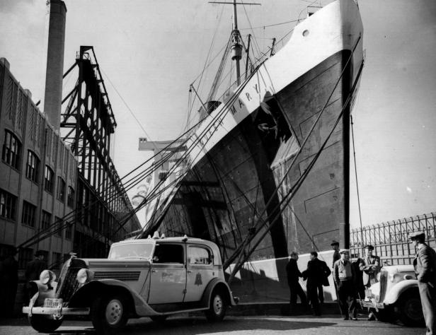 Das Schiff „Mary“ liegt im Hafen, davor stehen mehrere Männer und ein Auto.