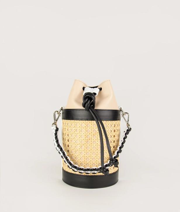 Eine Eimerhandtasche aus Rattan mit schwarzen und beigen Lederakzenten.