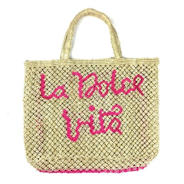 Eine gehäkelte Strandtasche mit der pinkfarbenen Aufschrift „La Dolce Vita“.