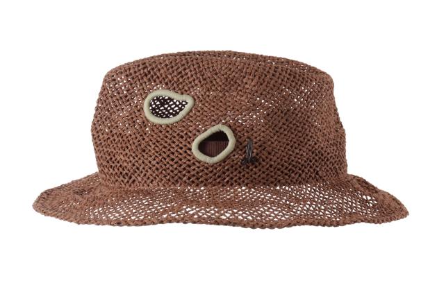 Ein brauner Strohhut mit Löchern und hellgrünen Rändern.
