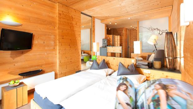 Ein Schlafzimmer mit Holzwänden und zwei Betten mit einer Zeitschrift darauf.