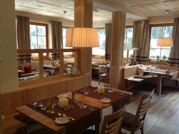 Einladender Speisesaal mit Holztischen und gedeckten Tischen.