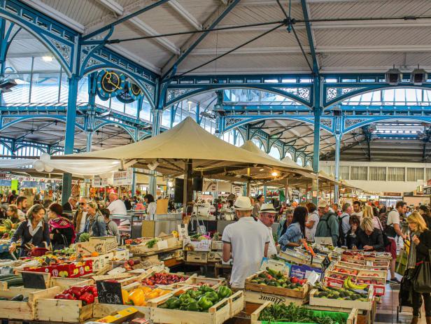 Ein belebter Markt mit Menschen, die an Ständen mit Obst und Gemüse einkaufen.