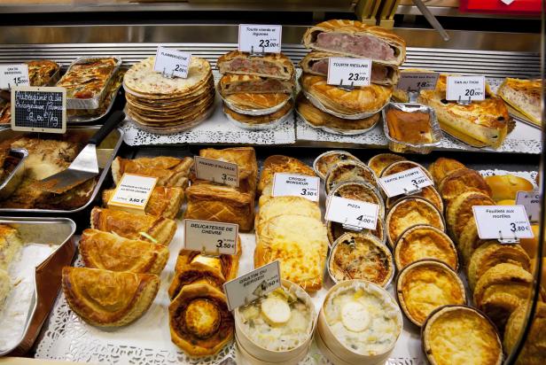 Eine Auslage mit verschiedenen Quiches, Tartes und Flammkuchen in einer Bäckerei.
