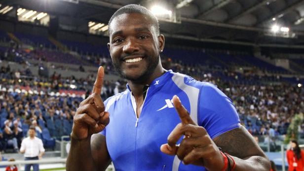 Ein lächelnder Sportler im blauen Trikot zeigt mit beiden Zeigefingern nach oben.