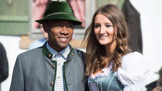 Ein Mann mit Trachtenhut und eine Frau im Dirndl lächeln in die Kamera.