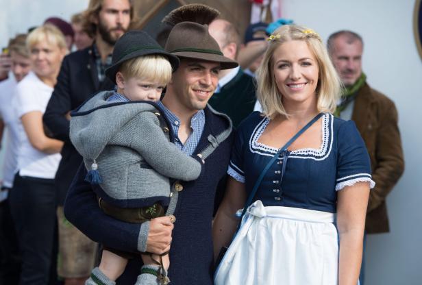 Eine Familie in Tracht, der Vater trägt ein Kind auf dem Arm.