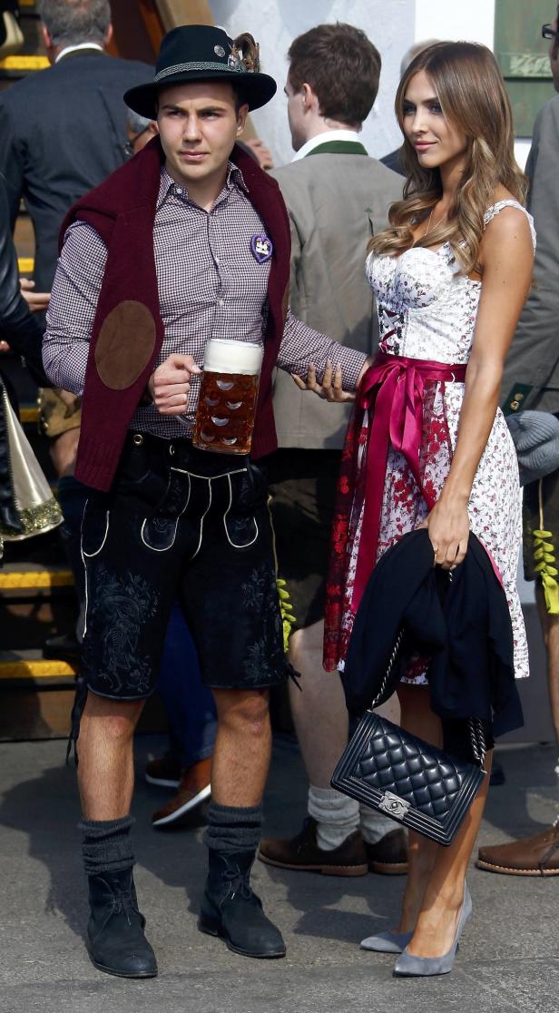 Ein Paar in Tracht hält Händchen, der Mann mit einem Bierkrug in der Hand.