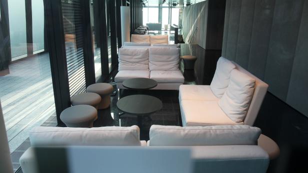 Ein modern eingerichteter Wartebereich mit weißen Sofas und runden Tischen.