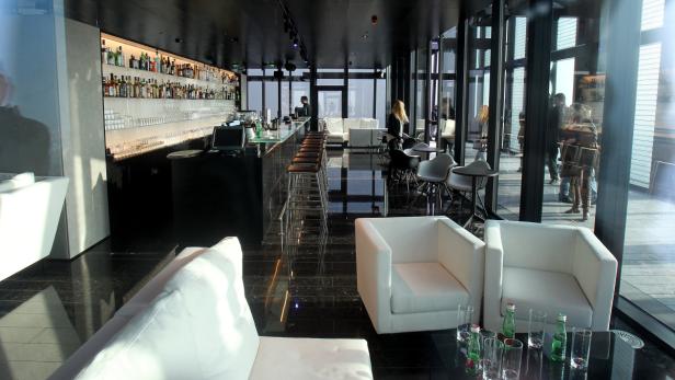 Eine Bar mit weißen Sofas und Stühlen bietet einen Ausblick durch die Fensterfront.