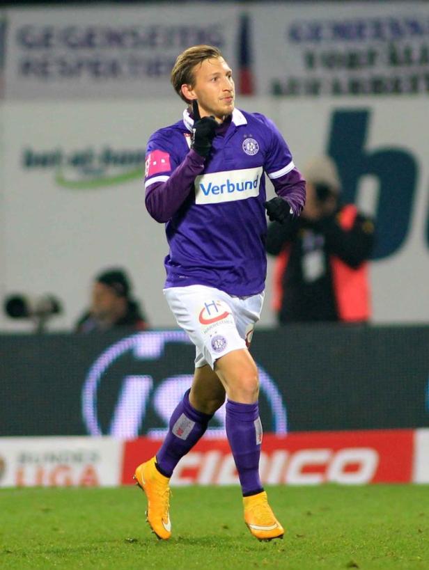 Ein Fußballspieler in lila-weißem Trikot und gelben Schuhen jubelt auf dem Spielfeld.