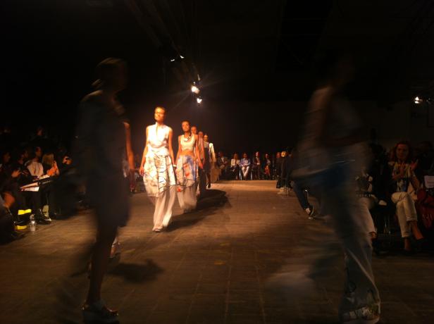 Models präsentieren Mode auf einem Laufsteg vor Publikum.