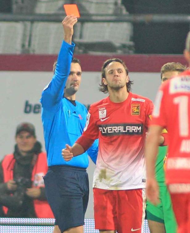 Ein Schiedsrichter zeigt einem Fußballspieler die rote Karte.