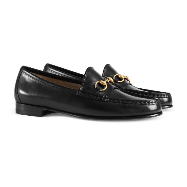 Ein Paar schwarze Lederslipper mit goldenen Zierelementen.