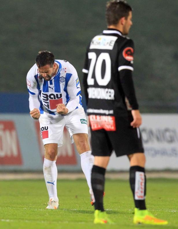 Ein Fußballspieler jubelt mit geballten Fäusten auf dem Spielfeld.