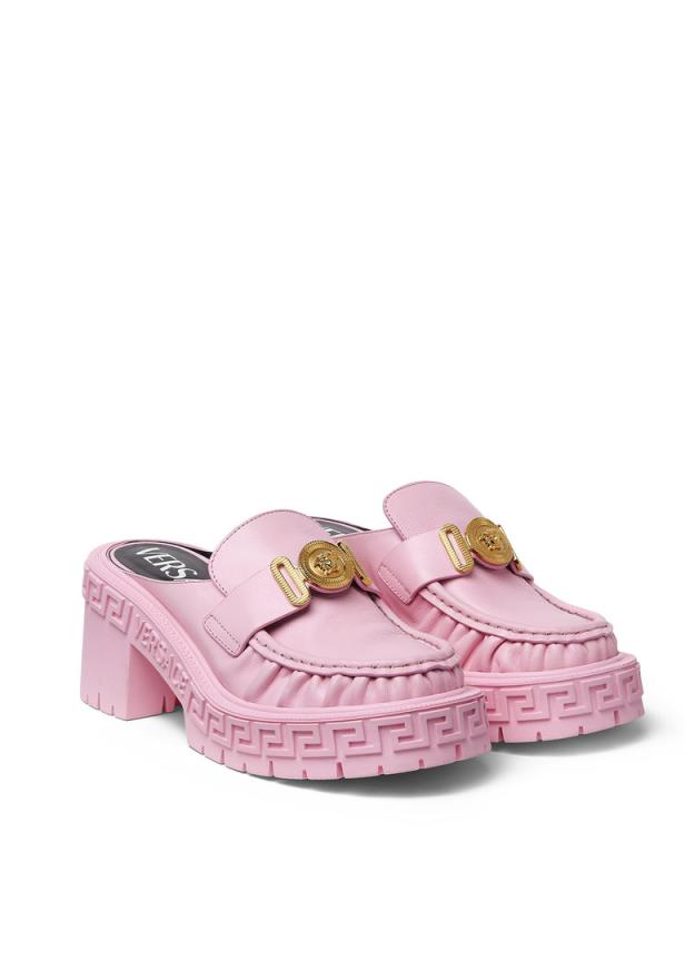 Ein Paar rosa Versace-Slipper mit goldenen Medusa-Logos und klobigen Sohlen.