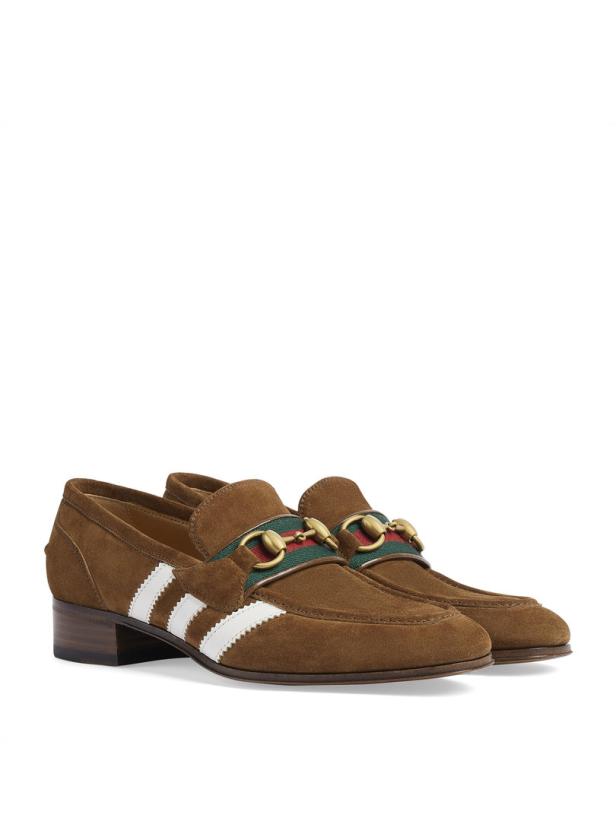 Ein Paar braune Wildleder-Loafer mit weißen Streifen und goldenen Schnallen.