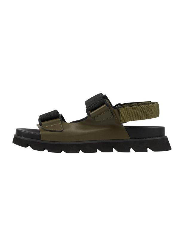 Eine olivgrüne Sandale mit schwarzen Riemen und einer dicken, schwarzen Sohle.