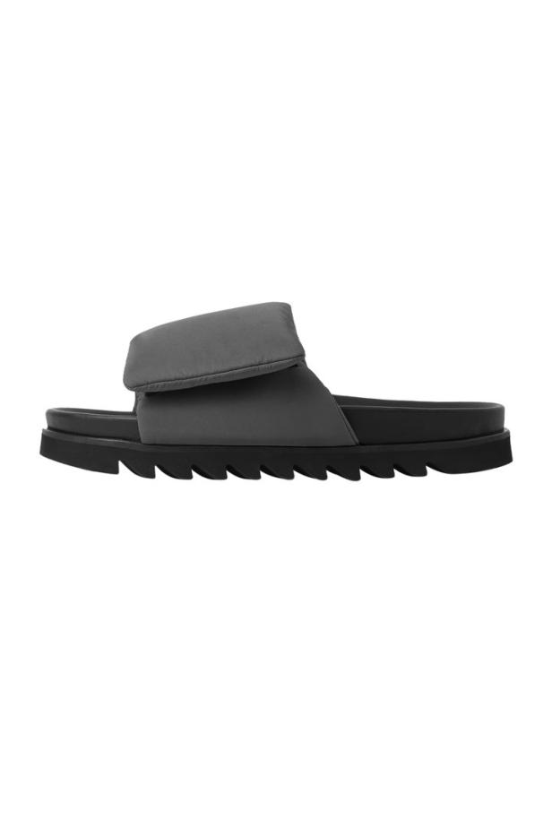 Eine graue Pantolette mit einem breiten Riemen und einer markanten Sohle.