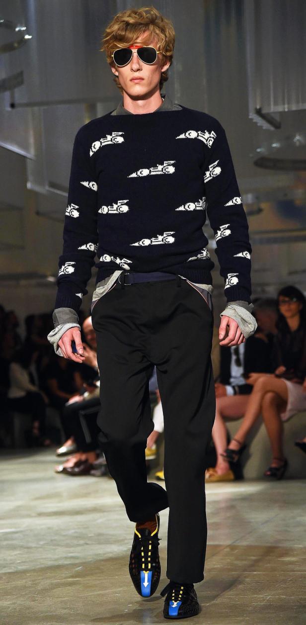 Ein Mann mit Sonnenbrille trägt einen Pullover mit Automotiven auf dem Laufsteg.