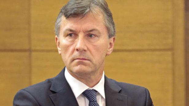 Ein Mann in Anzug und Krawatte blickt aufmerksam zur Seite.