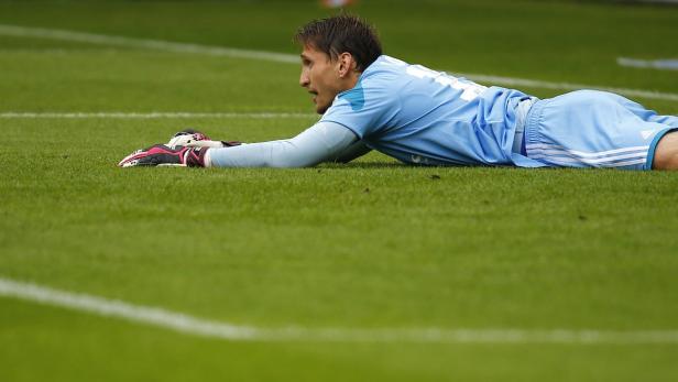 Ein Torwart liegt mit Handschuhen auf dem Rasen.