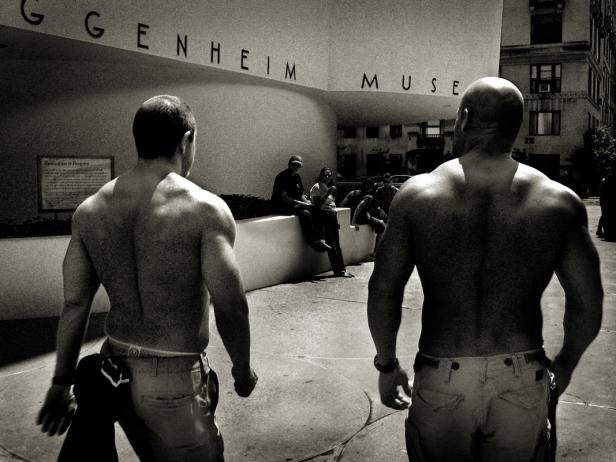 Zwei Männer ohne Hemd stehen vor dem Guggenheim Museum in New York.