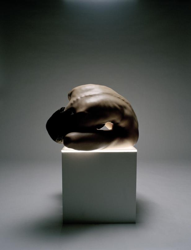 Eine Skulptur einer hockenden, in sich gekehrten menschlichen Figur auf einem Sockel.