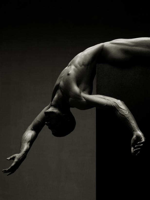 Ein muskulöser Mann beugt sich über einen schwarzen Block.