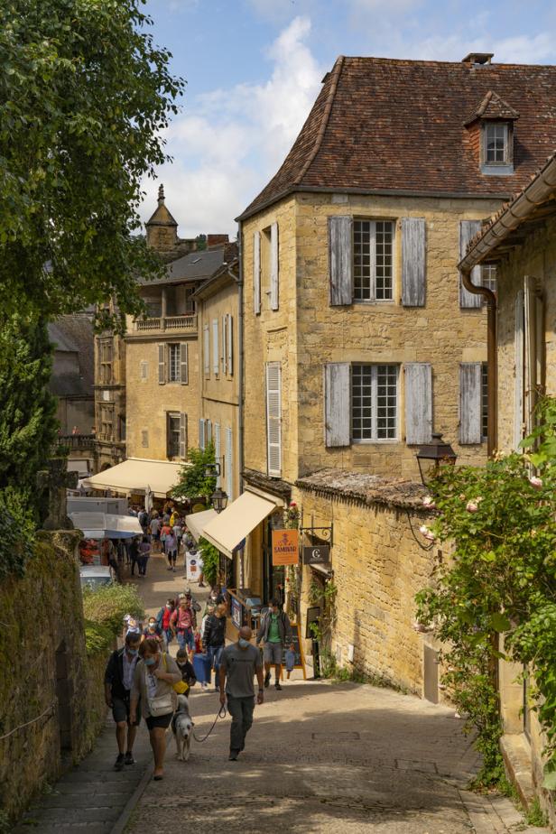 Eine belebte Straße in einer französischen Stadt mit Menschen und historischen Gebäuden.