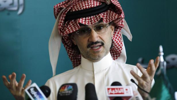 Ein Mann mit traditioneller Kopfbedeckung spricht vor Mikrofonen.