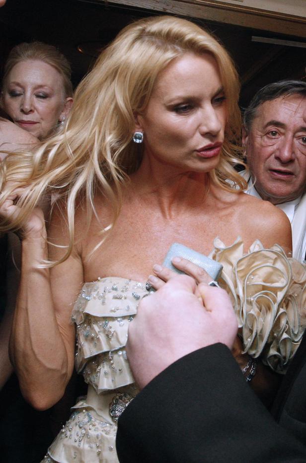Eine blonde Frau im Abendkleid erhält einen Ring in einer Schmuckschatulle.