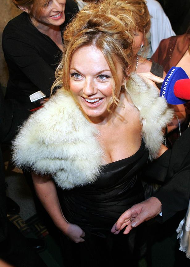 Geri Halliwell lächelt mit einem weißen Pelzkragen und einem schwarzen Kleid.
