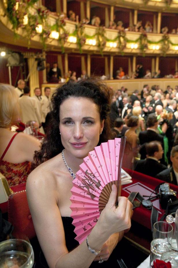 Andie MacDowell mit einem rosa Fächer bei einer Veranstaltung in einem Opernhaus.