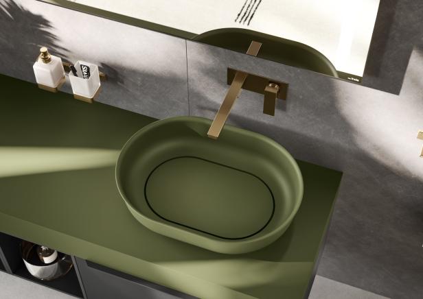 Ein modernes Badezimmer mit einem grünen Aufsatzwaschbecken und goldenen Armaturen.