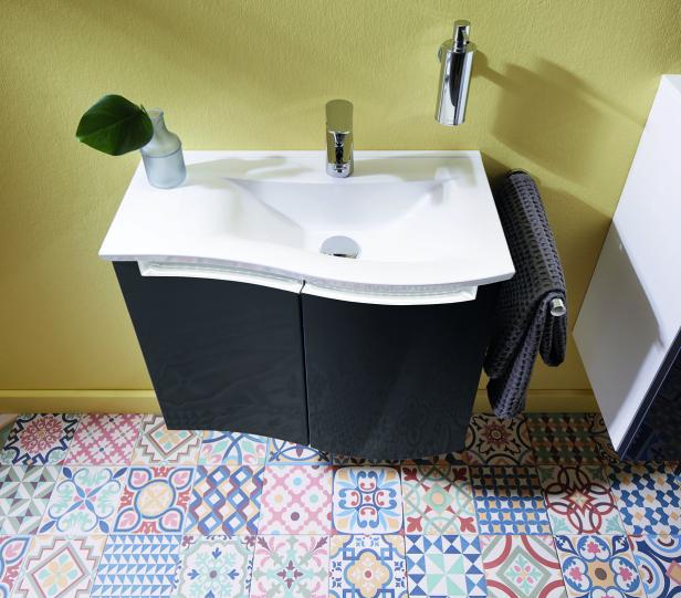 Ein Badezimmerwaschtisch mit grauen Schränken und einem bunten Fliesenboden.
