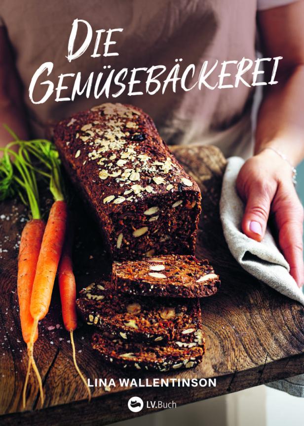 Ein Laib Gemüsebrot mit Karotten auf einem Holzbrett, präsentiert von einer Person.