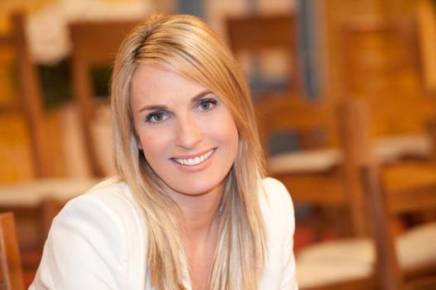 Eine Frau mit blonden Haaren lächelt in die Kamera.