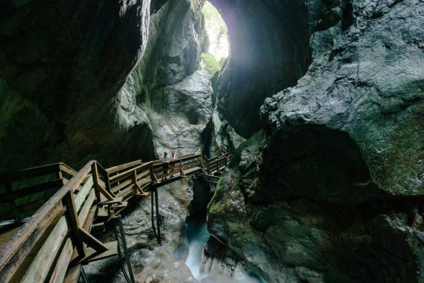 Zwei Personen auf einem Holzsteg in einer tiefen, engen Schlucht.