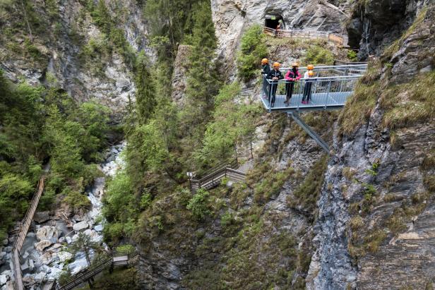 Eine Gruppe von Personen mit Helmen steht auf einer Aussichtsplattform in einer Schlucht.