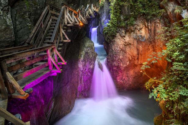 Eine Schlucht mit einem Wasserfall, der von Holzstegen überspannt wird.