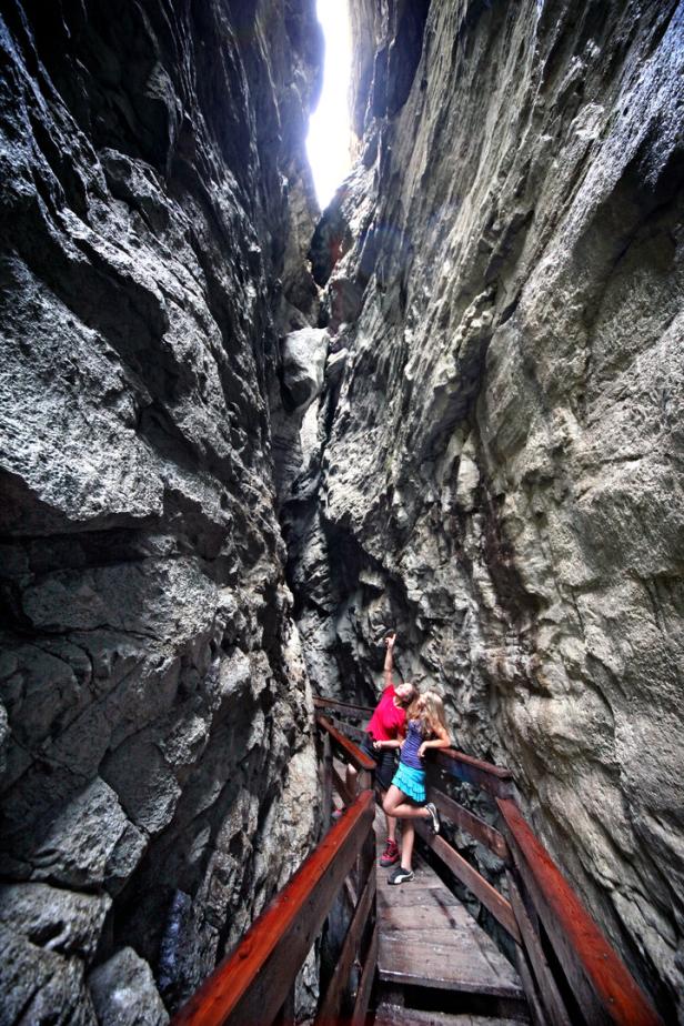 Zwei Personen stehen auf einem Holzsteg in einer engen Schlucht.