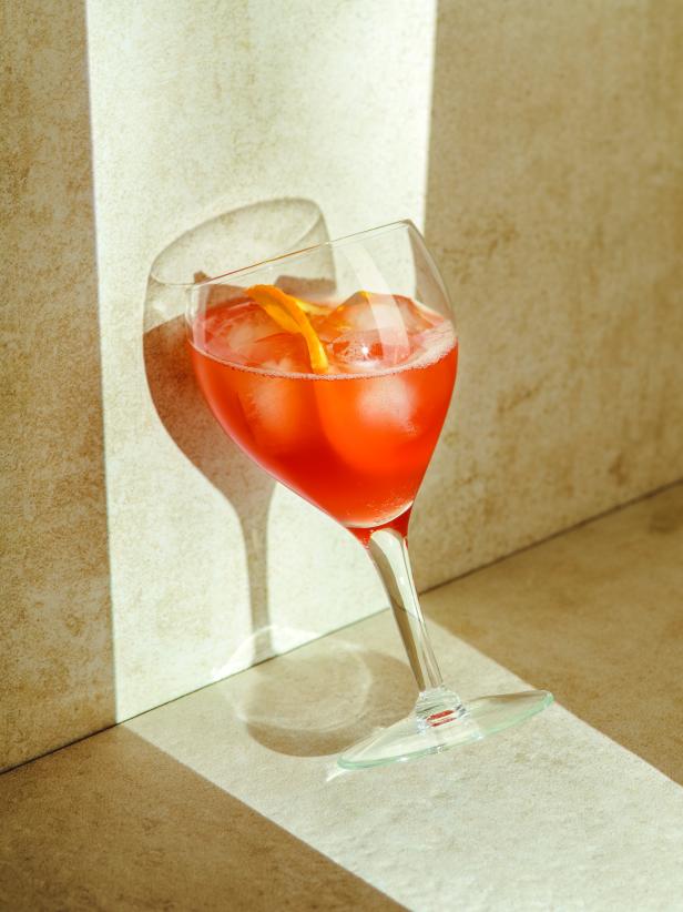 Ein Aperol Spritz mit Eiswürfeln und einer Orangenscheibe in einem Weinglas.