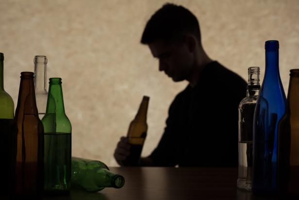 Ein junger Mann schaut auf eine Bierflasche.